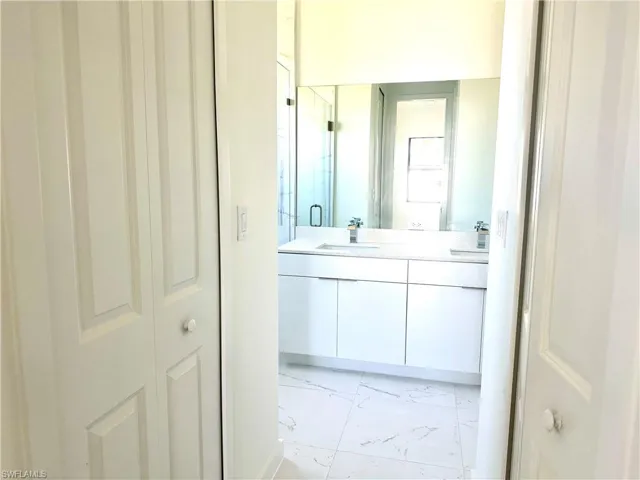 Full bathroom featuring double vanity, marble finish floor, a sink, and a stall shower