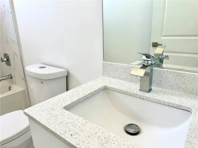 Bathroom with washtub / shower combination, vanity, and toilet