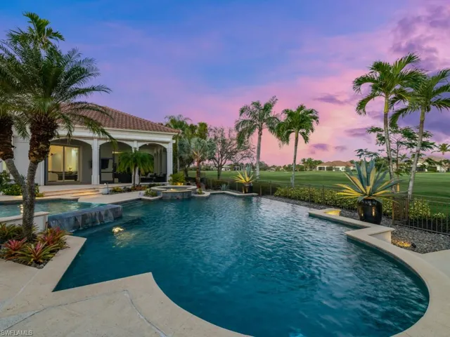 Pool at dusk featuring pool water feature and an in ground hot tub