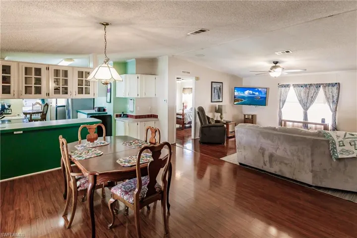 Dining area with ceiling fan, wood-type flooring, lofted ceiling, and a textured ceiling