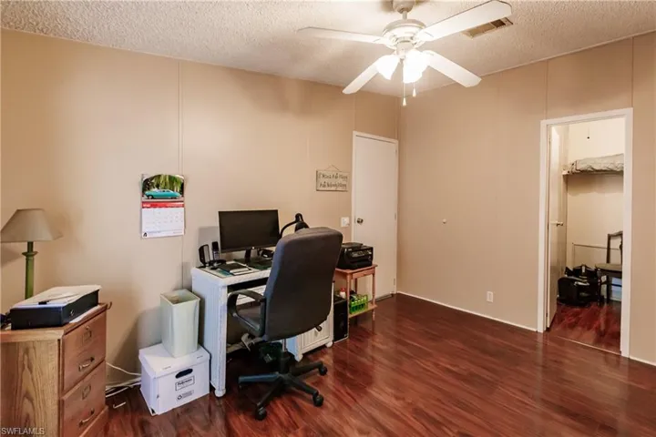 Office with ceiling fan, dark wood-type flooring, and a textured ceiling