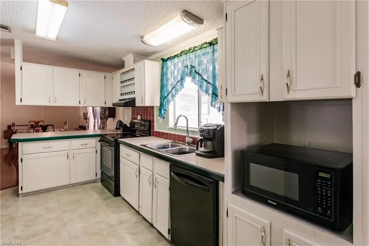 Kitchen with backsplash, a textured ceiling, sink, black appliances, and white cabinets