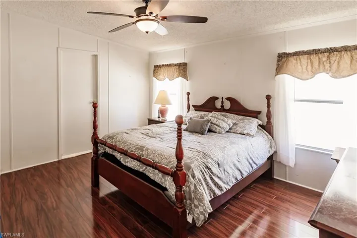 Bedroom with ceiling fan, dark hardwood / wood-style floors, and a textured ceiling
