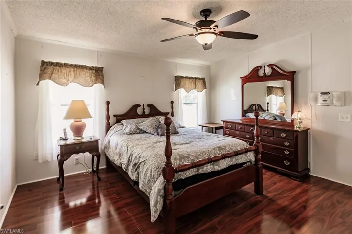 Bedroom with a textured ceiling, dark hardwood / wood-style flooring, and ceiling fan