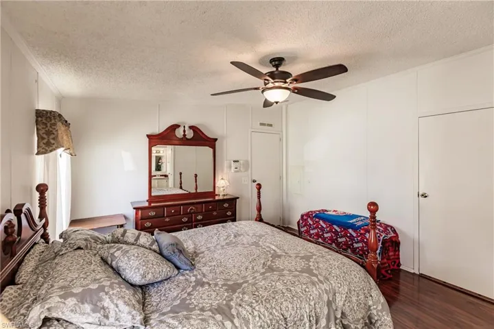 Bedroom with hardwood / wood-style floors, a textured ceiling, ceiling fan, and ornamental molding