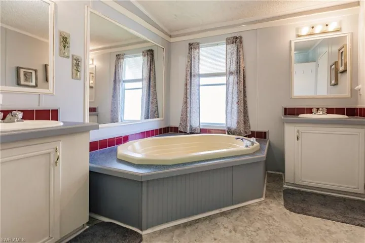 Bathroom with vanity, ornamental molding, a bathing tub, and a textured ceiling