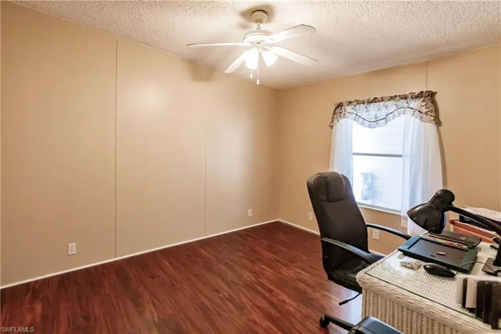 Unfurnished office featuring ceiling fan, dark hardwood / wood-style floors, and a textured ceiling