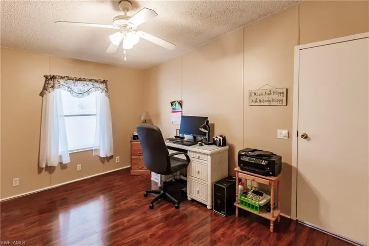 Office area with a textured ceiling, dark hardwood / wood-style flooring, and ceiling fan