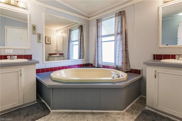 Bathroom with a bath, crown molding, lofted ceiling, a textured ceiling, and vanity