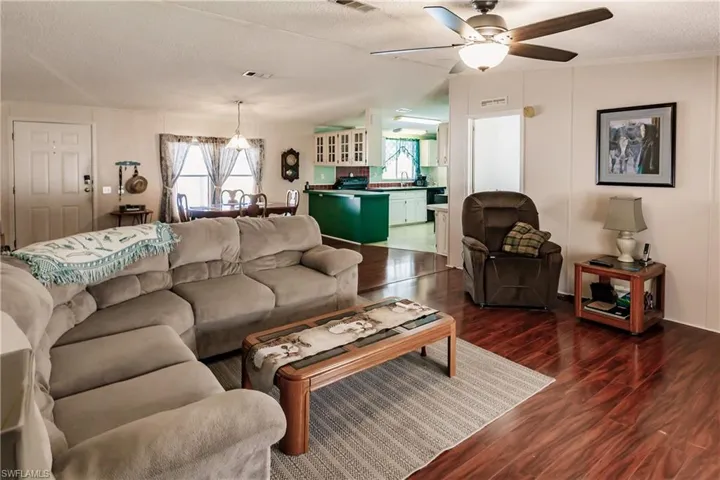 Living room featuring ceiling fan, sink, dark hardwood / wood-style flooring, and a textured ceiling
