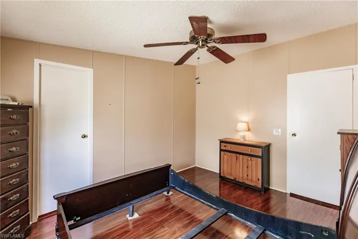 Bedroom with a textured ceiling, dark hardwood / wood-style floors, and ceiling fan