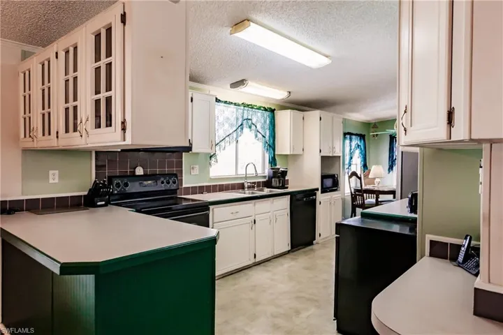 Kitchen featuring black appliances, white cabinetry, sink, and a textured ceiling