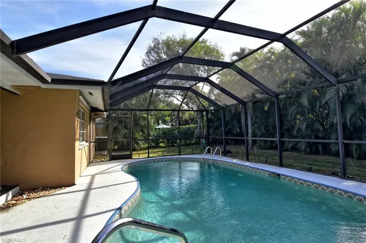 View of pool with glass enclosure and a patio