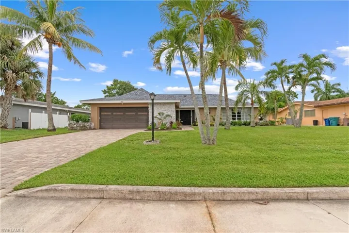 Single story home with an attached two-car garage and long paver driveway.
