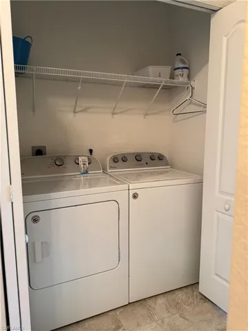 Dedicated laundry closet featuring a washer and dryer, wire shelving, and neutral tone flooring