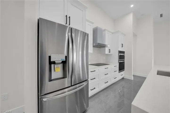 Kitchen with marble finish floor, stainless steel appliances, wall chimney range hood, and light countertops