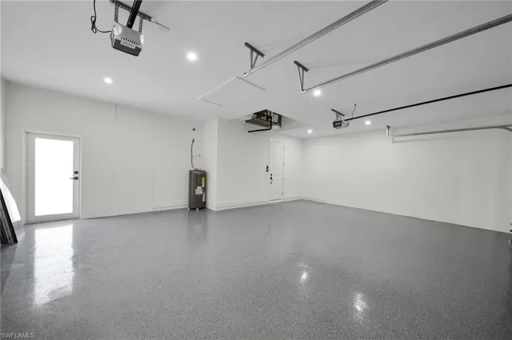 Garage featuring a garage door opener and electric water heater