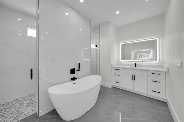 Bathroom with marble finish floor, a marble finish shower, recessed lighting, a soaking tub, and vanity
