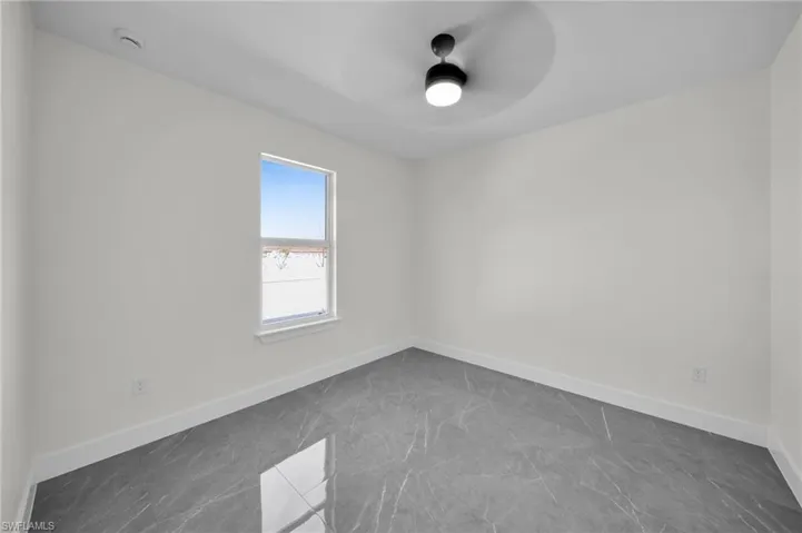 Empty room featuring a ceiling fan and baseboards