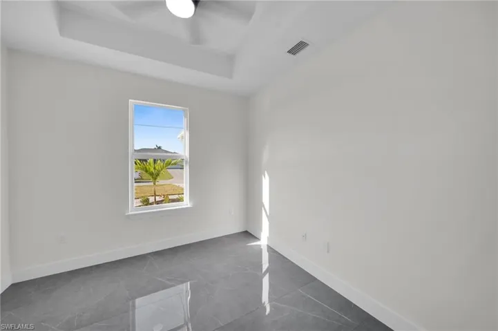 Spare room featuring a raised ceiling, visible vents, ceiling fan, and baseboards