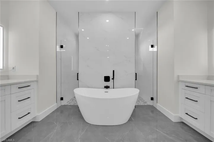Full bathroom with marble finish floor, a marble finish shower, a freestanding tub, and vanity