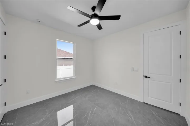 Empty room featuring ceiling fan and baseboards
