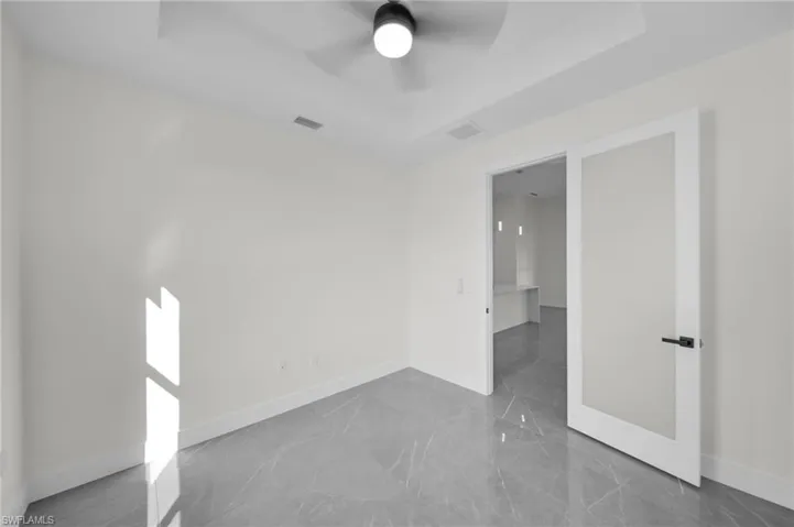 Unfurnished room featuring a tray ceiling, marble finish floor, visible vents, and baseboards