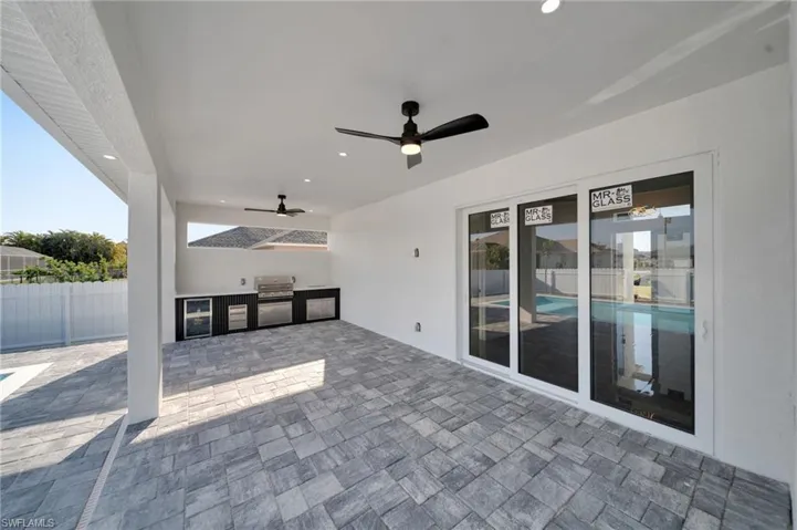 View of patio / terrace with an outdoor kitchen, a ceiling fan, wine cooler, grilling area, and fence