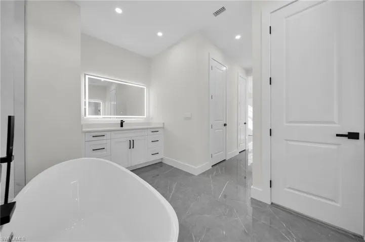 Full bath with baseboards, marble finish floor, a freestanding bath, vanity, and recessed lighting
