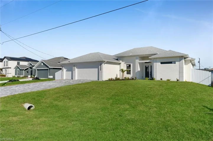 View of front of home featuring decorative driveway, stucco siding, a front yard, fence, and a garage