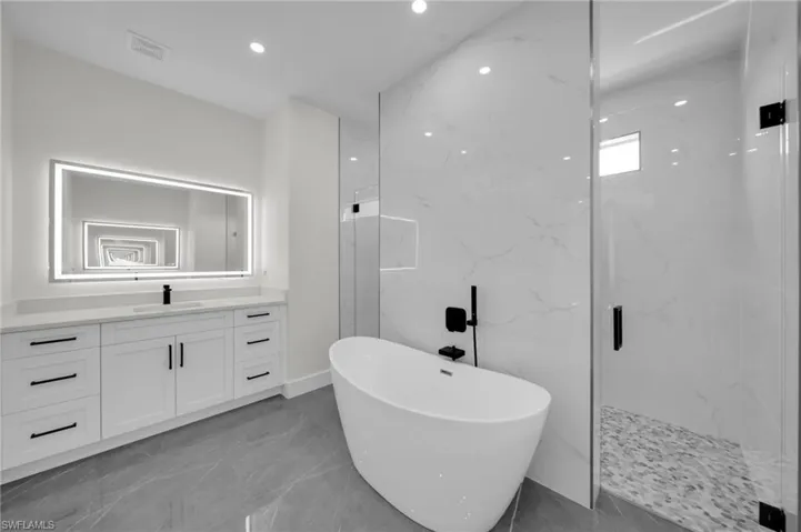 Full bath featuring marble finish floor, a marble finish shower, visible vents, a freestanding bath, and vanity