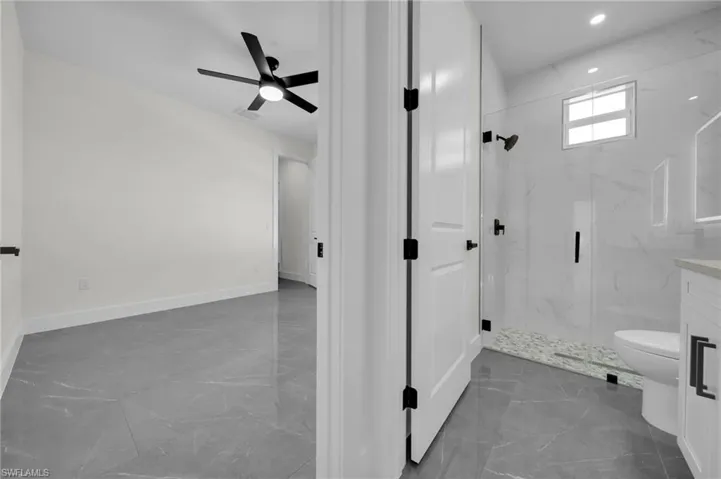 Full bath with toilet, a ceiling fan, baseboards, marble finish floor, and a marble finish shower