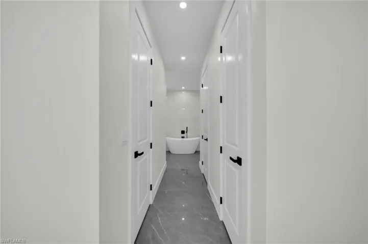 Hall with recessed lighting and marble finish floor