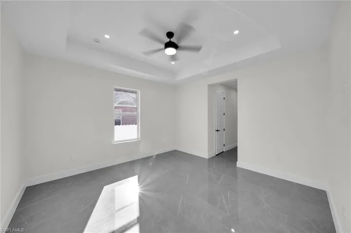 Spare room with ceiling fan, recessed lighting, a raised ceiling, and baseboards