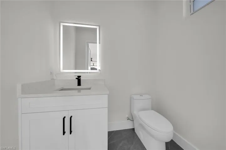 Bathroom featuring baseboards, vanity, and toilet