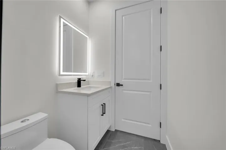 Bathroom with marble finish floor, vanity, and toilet