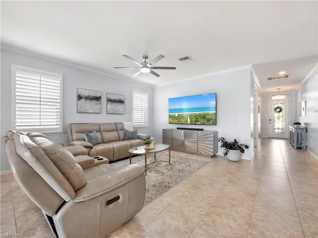 Living room featuring ornamental molding, a ceiling fan, plenty of natural light, and light tile patterned floors