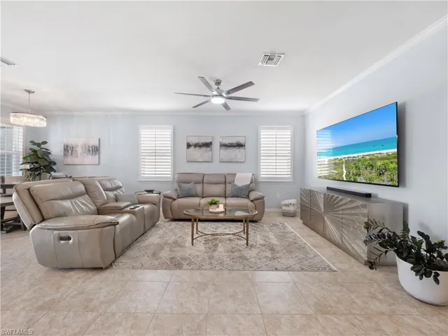 Living room with ornamental molding, ceiling fan, plenty of natural light, light tile patterned floors, and hanging lights