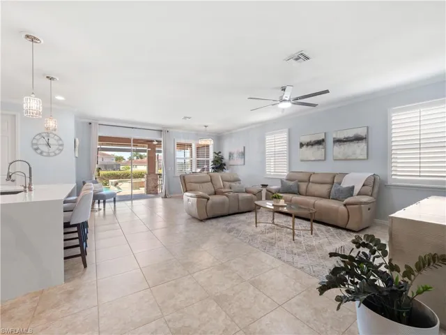Living area with crown molding, ceiling fan, and light tile patterned flooring