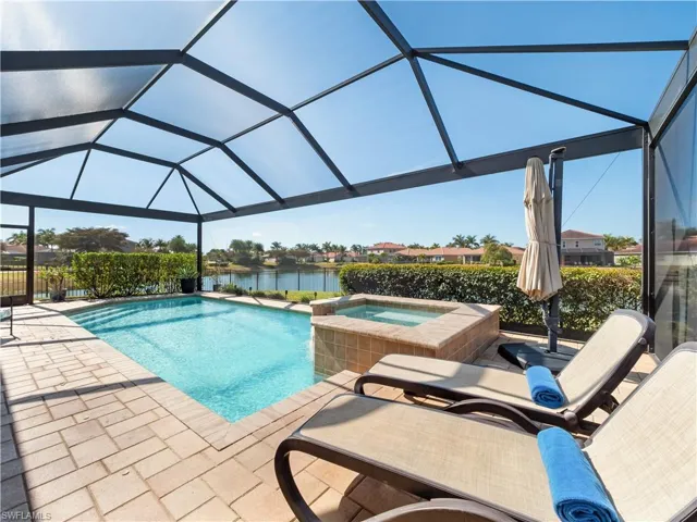 Integrated pool / spa with glass enclosure, a sunroom, a water view, and a patio area