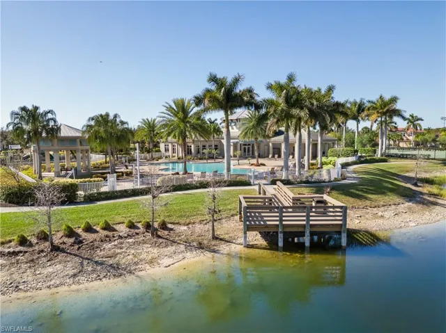 Dock with a lawn, a patio area, a water view, and a community pool