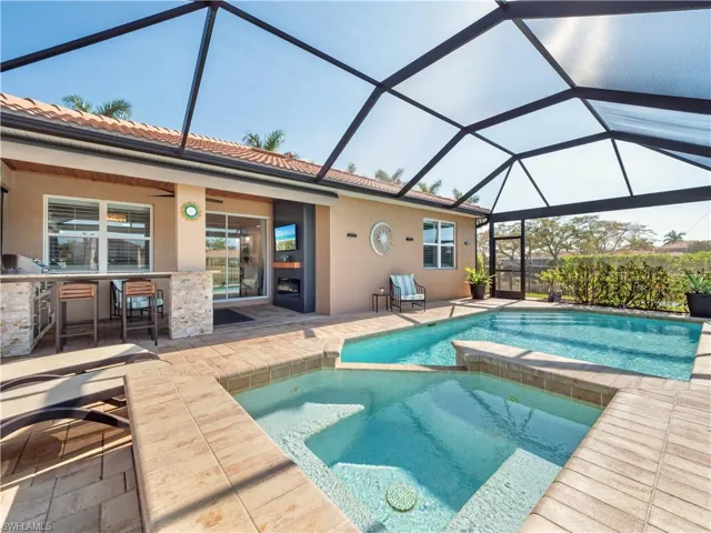 Integrated pool / spa featuring a patio area, a sunroom, a lanai, and exterior kitchen