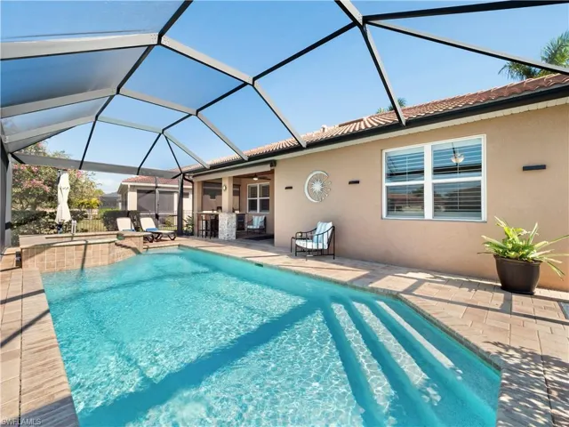 Combined pool / hot tub featuring a sunroom, a patio area, and glass enclosure