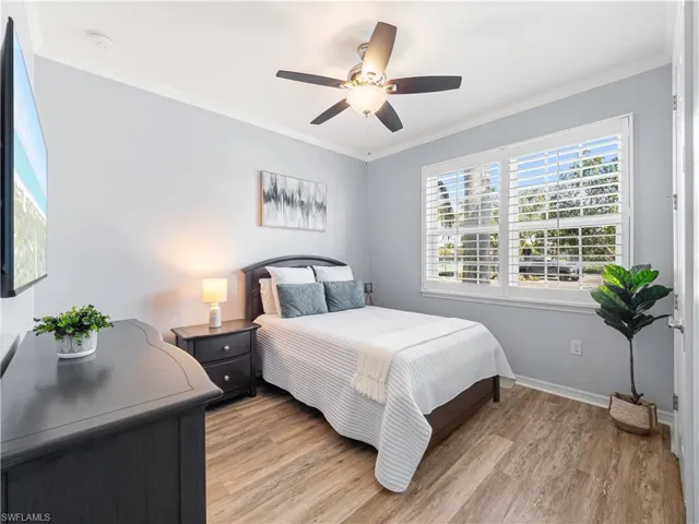 Bedroom with light wood-style floors, crown molding, and ceiling fan