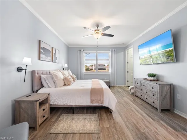 Bedroom featuring light wood finished floors, a ceiling fan, and crown molding