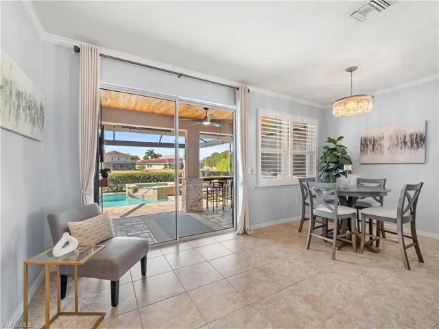Dining area with crown molding, a sunroom, ceiling fan, light tile patterned flooring, and hanging lights