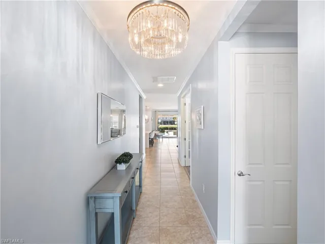 Hallway featuring crown molding, suspended lighting, and light tile patterned floors