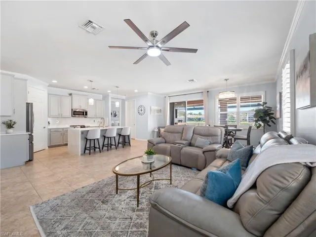Living room with crown molding, ceiling fan, recessed lighting, and light tile patterned floors