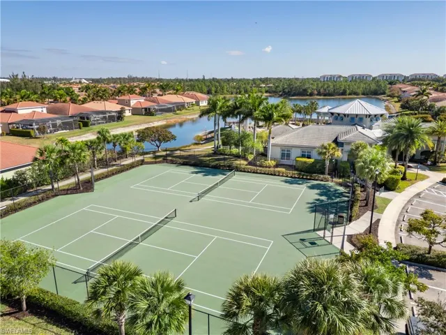 View of tennis court featuring a residential view and a water view