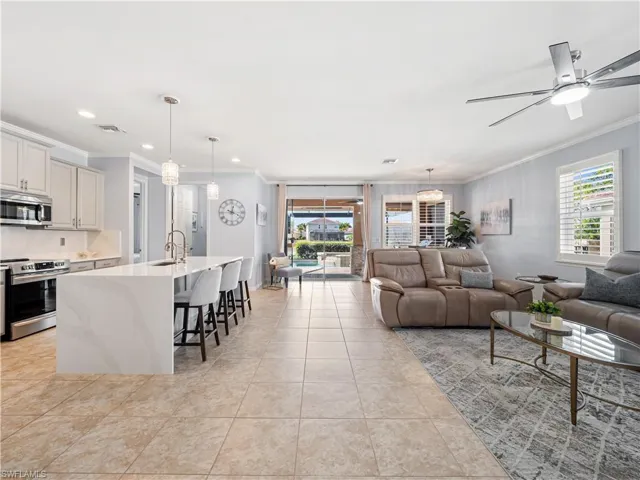 Living area with crown molding, ceiling fan, and light tile patterned flooring